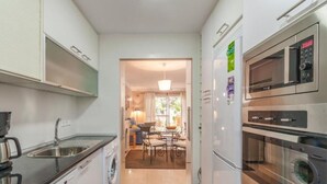 A compact kitchen with a washing machine, a coffee maker, and a microwave. - Beach Access Apt in Playa Real | Pool & Terrace - Pass the Keys (Marbella)