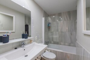 A modern bathroom with a large mirror, a sink, a toilet, and a shower area. - Beach Access Apt in Playa Real | Pool & Terrace - Pass the Keys (Marbella)
