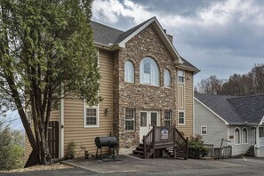 A two-story house with stone and siding exterior, a front porch, and a garage. - Gatlinburg*Amazing View*Sleeps 11*Hot tub (GATLINBURG)