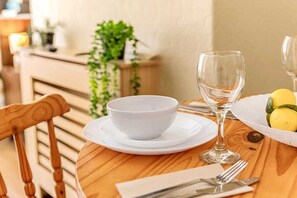 A wooden dining table with a white bowl, a wine glass, and a plate with a yellow item, possibly food. - Rosewick Villa wt Office, Garden & Free Parking (Nottingham)