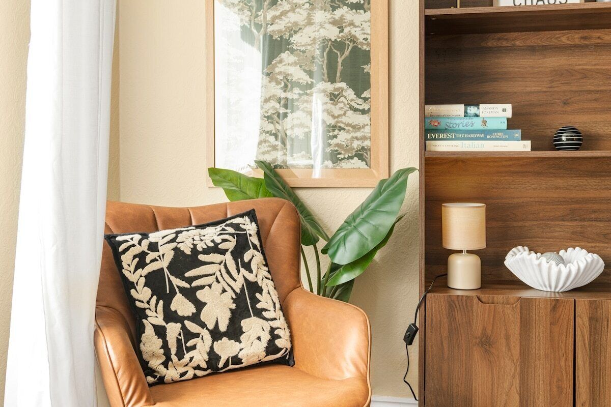 Ein Zimmer mit Ledersessel, Bücherregal mit Büchern, Lampe und einer dekorativen Muschel auf einem Holznachttisch.