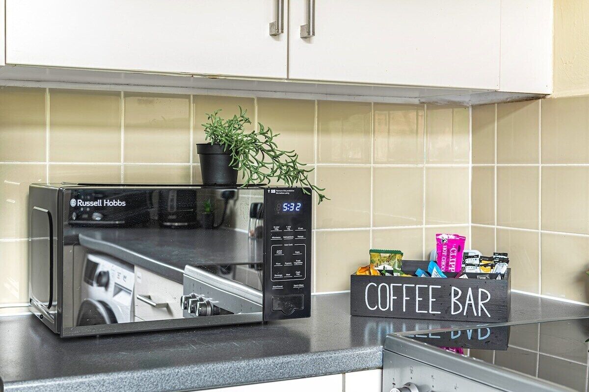 A kitchen with a microwave, a coffee bar, and a potted plant.