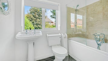 A bathroom with a pedestal sink, toilet, and a glass-enclosed shower area.