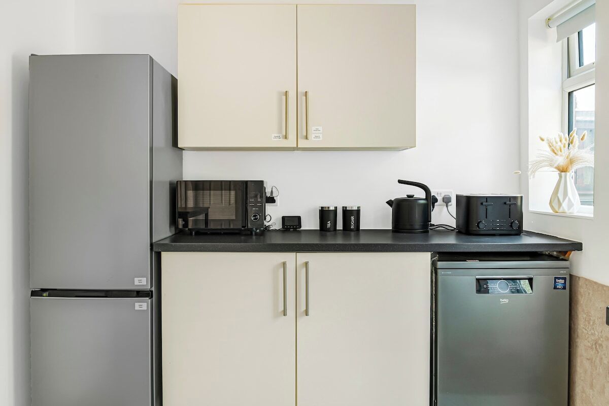 Una cocina funcional equipada con refrigerador, microondas, tostadora y lavavajillas.
