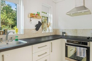 A kitchen with a sink, stove, oven, and a window with a view of greenery. - Villa near Nottingham Hospital w/ Gardens (Nottingham)