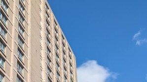 A tall building with a modern architectural design, featuring a grid of windows and a beige facade. - Charming 2 bedroom apartment with AC in adorable Detroit (Detroit)