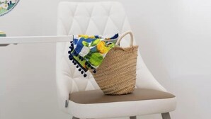 Una silla blanca tapizada con un bolso tejido encima.