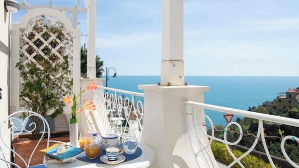 Un balcón con una mesa dispuesta para el desayuno, con vista al mar.