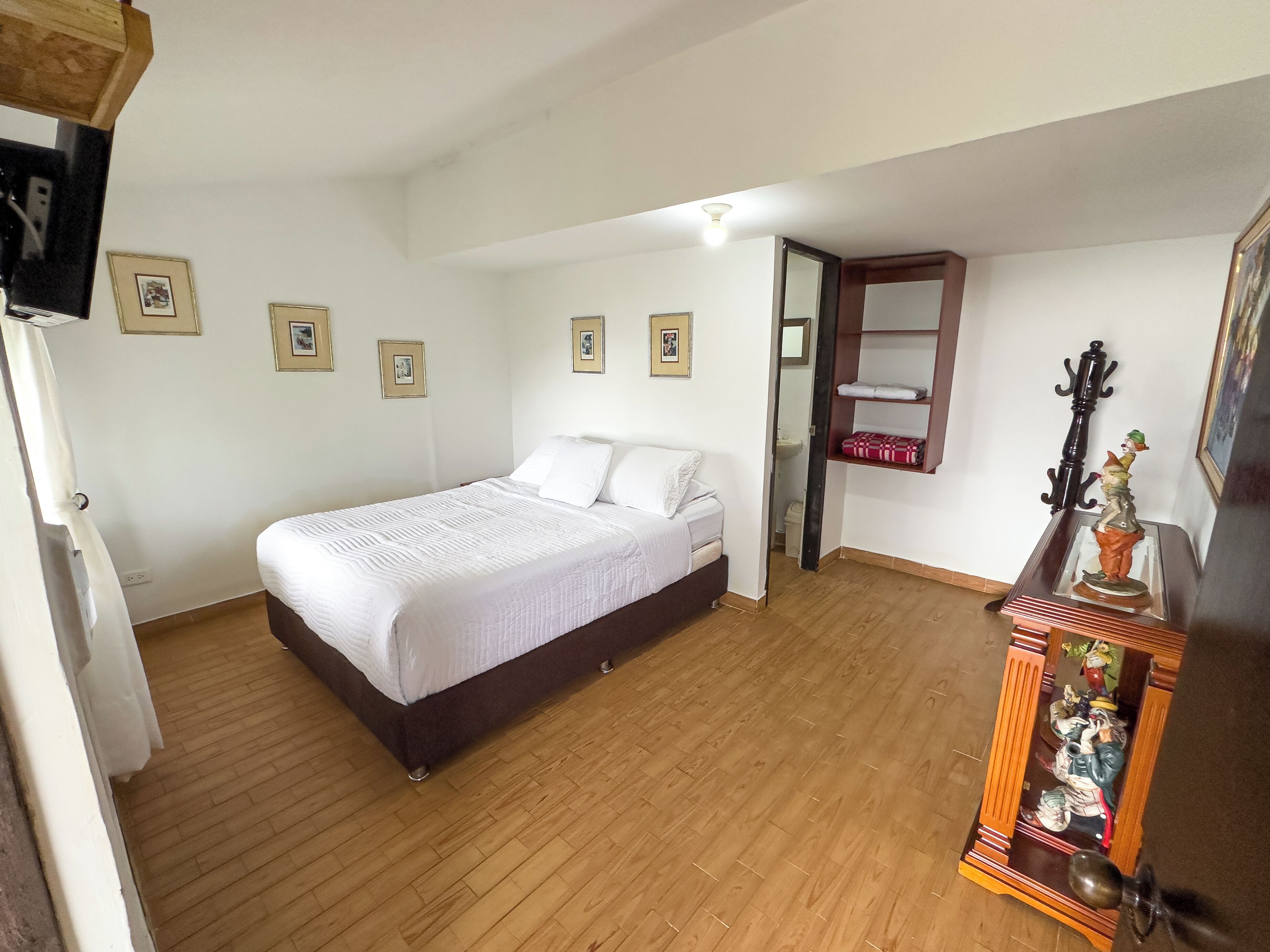 Un dormitorio con cama, suelo de madera, armario y espejo.