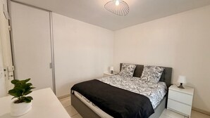 Una camera da letto con un letto, comodini, una lampada da comodino, una pianta in vaso e un lampadario.