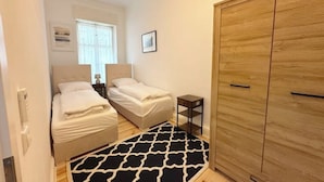 Una camera da letto con due letti, un armadio in legno, un comodino e un tappeto decorato.
