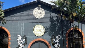 Un edificio con fachada oscura, dos puertas arqueadas y una puerta central. Dos figuras decorativas de sirenas flanquean la puerta central.