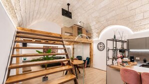 Una cocina moderna con una escalera de madera, un comedor con sillas y una isla de cocina con taburetes de bar.