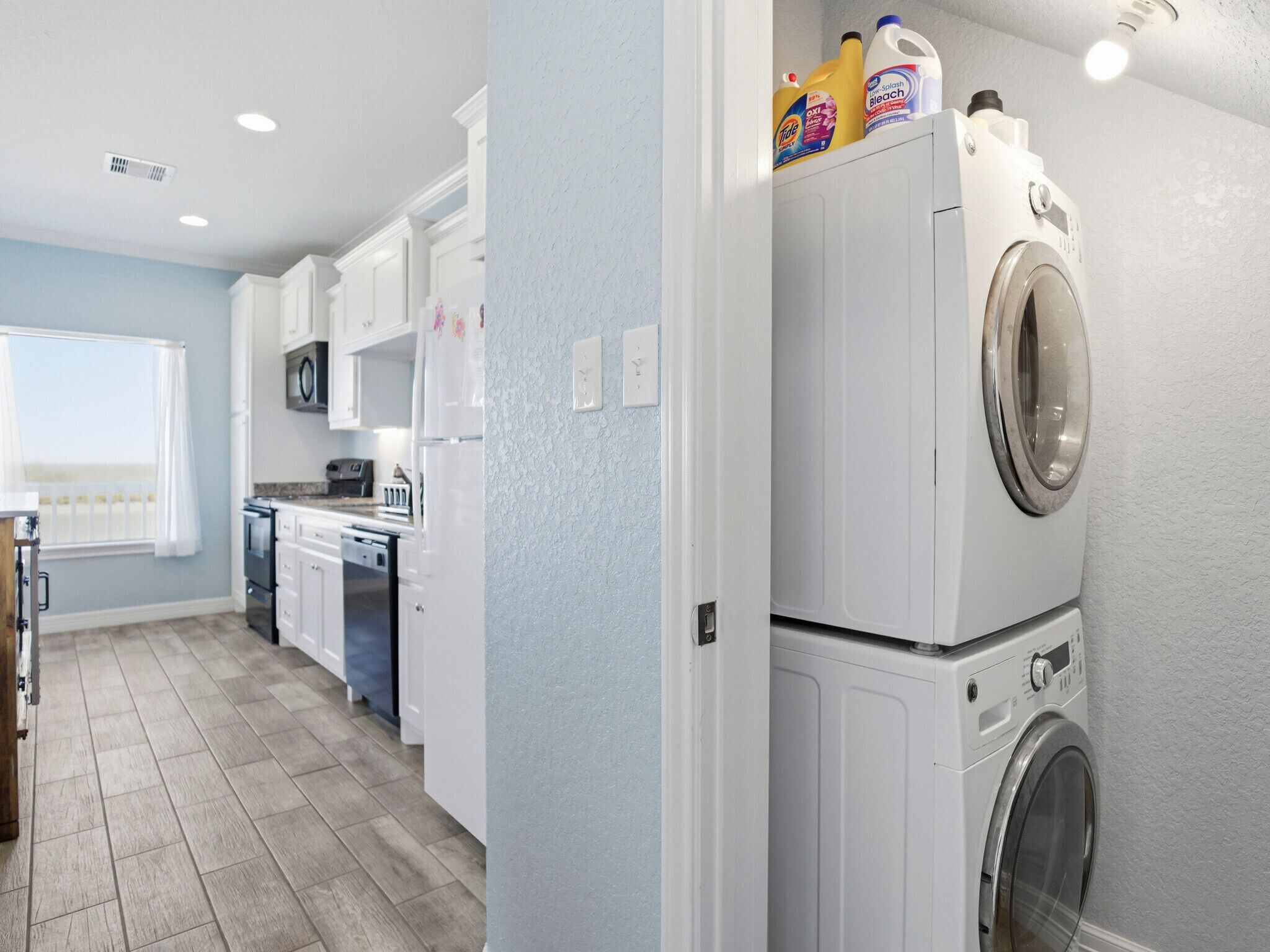 A modern kitchen with white cabinets, a built-in oven, and a washing machine.
