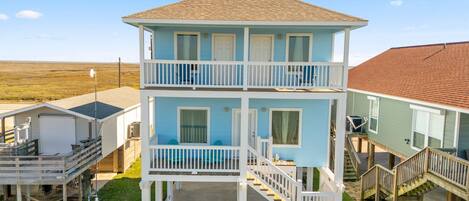A two-story building with a balcony on the upper floor, a covered porch on the ground floor, and a staircase connecting the two levels.