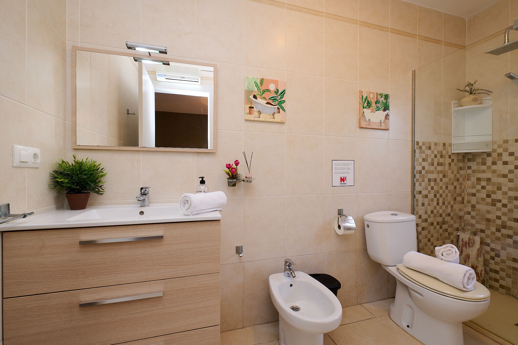A modern bathroom with a sink, mirror, bidet, toilet, and decorative tiles.
