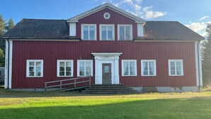 A two-story red building with a white door and multiple windows. - Apartment at country side. Spa facility and much more out in swedish woods. (säffle)