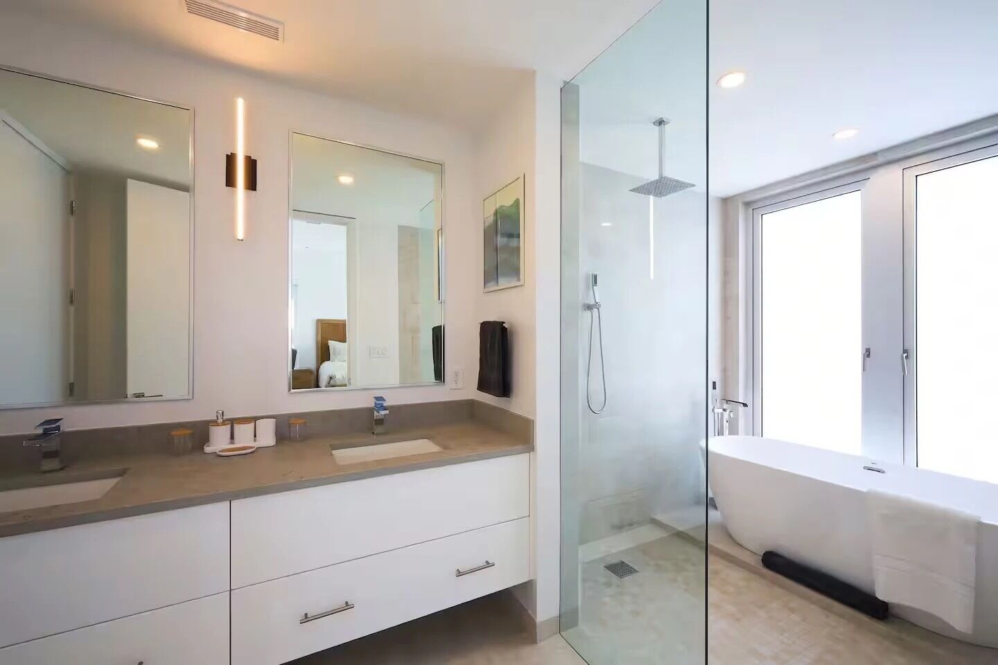 Ein modernes Badezimmer mit einer Duschkabine aus Glas, einem großen Spiegel und einer Badewanne.