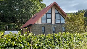 Ein modernes Haus mit geneigtem Dach, großen Fenstern und Steinwänden.