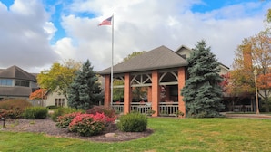 Un bâtiment à la façade en briques, un mât sur lequel flotte le drapeau américain, et un jardin bien entretenu avec des arbustes et une pelouse.