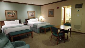 A hotel room with two beds, a desk, a chair, and a small table.