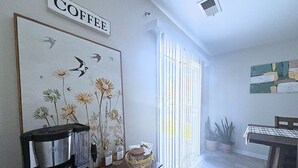 Eine Küche mit einer Kaffeemaschine, einem gerahmten Blumenbild und einem Schild mit der Aufschrift 'COFFEE'.