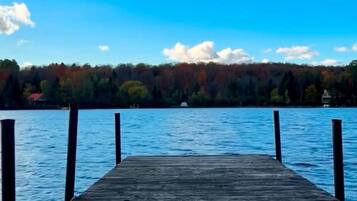 A wooden pier extending into a calm lake with a forested shoreline in the background.