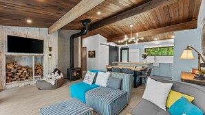 A cozy living room with a fireplace, a dining area, and a kitchen.