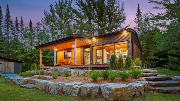 A modern house with a wooden exterior, large windows, and a stone garden.