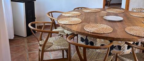 Comedor con una mesa redonda de madera, individuales tejidos y sillas de mimbre.
