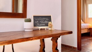 A wooden bench with a welcome sign, a potted cactus, and a honey jar.