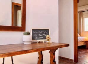 A wooden bench with a welcome sign, a potted cactus, and a honey jar.
