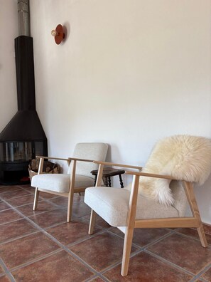 A room with two upholstered chairs, a fireplace, and a tiled floor.