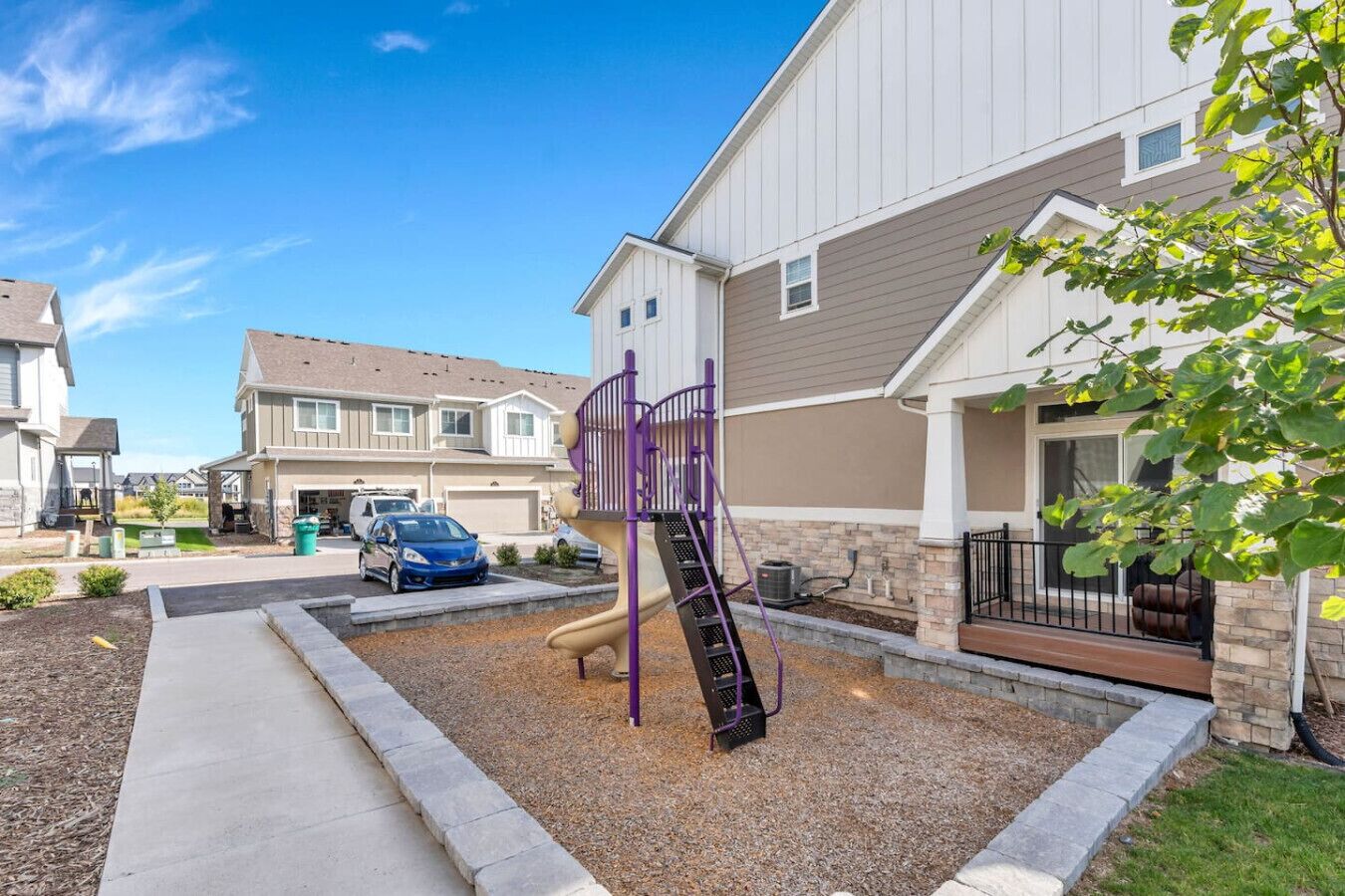 A residential area with a playground, a driveway, and houses.