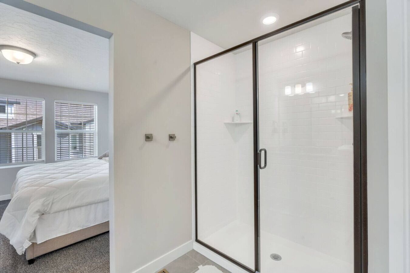 A bedroom with a bed, a walk-in closet with a sliding door, and a window with blinds.