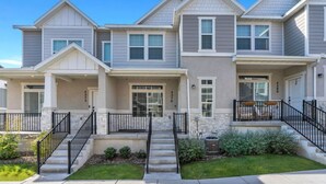 A row of townhouses with a front porch, a stone foundation, and a small front yard.