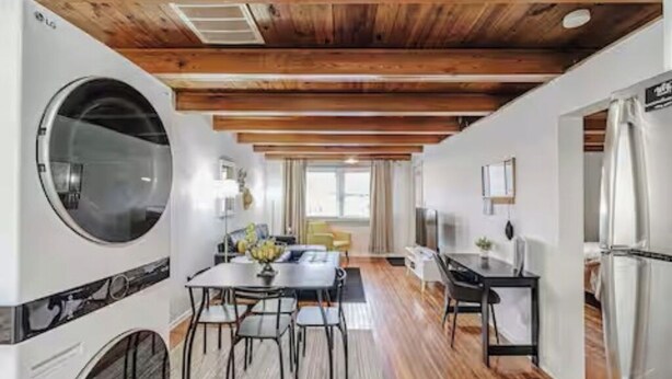 Een moderne keuken met een groot LG apparaat, houten balken in het plafond en een eethoek met een tafel en stoelen.