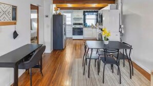 Een moderne keuken met witte kasten, een zwarte koelkast en een eethoek met een zwarte tafel en stoelen.