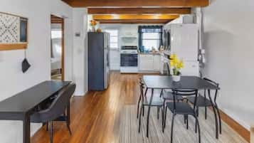 A modern kitchen with white cabinets, a black refrigerator, and a dining area with a black table and chairs.