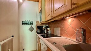 Een kleine keuken met houten kastjes, een zwart aanrecht en een betegelde spatwand.