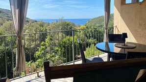 A balcony with a table and chairs, overlooking a scenic view of hills and the sea. - Three-room 2-bedroom apartment and sea view terrace (Rio Nell'elba)