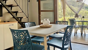 A dining area with a table and chairs, a vase on the table, and a staircase in the background. - Three-room 2-bedroom apartment and sea view terrace (Rio Nell'elba)