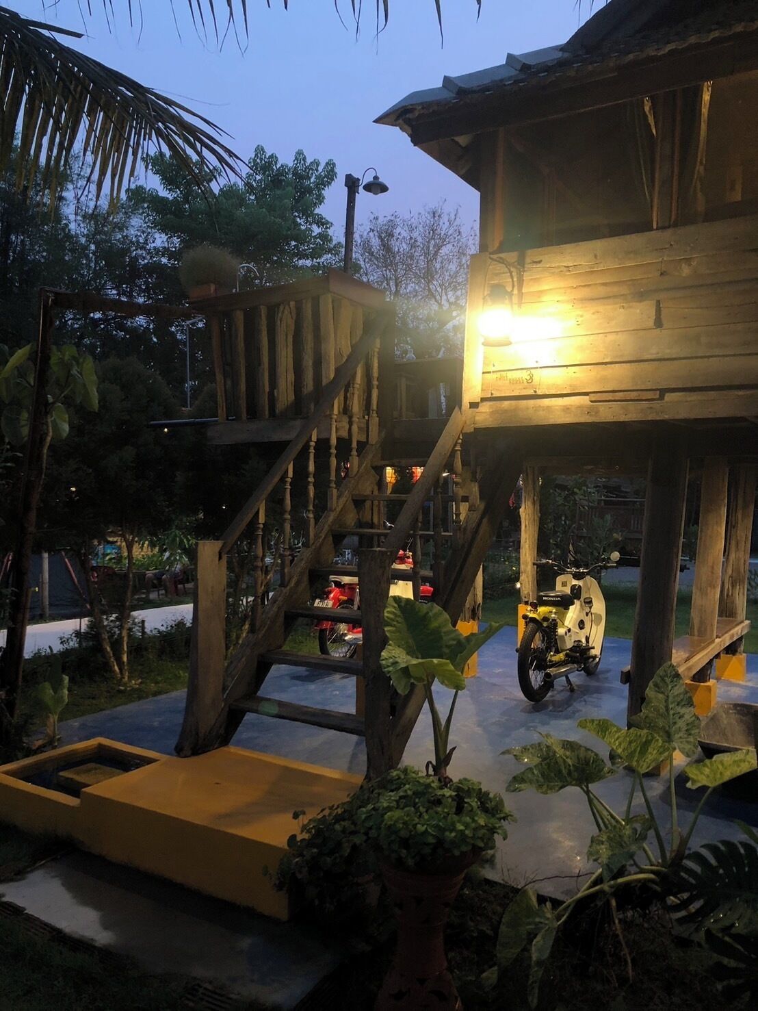 A wooden structure with a staircase, a motorcycle, and a potted plant.