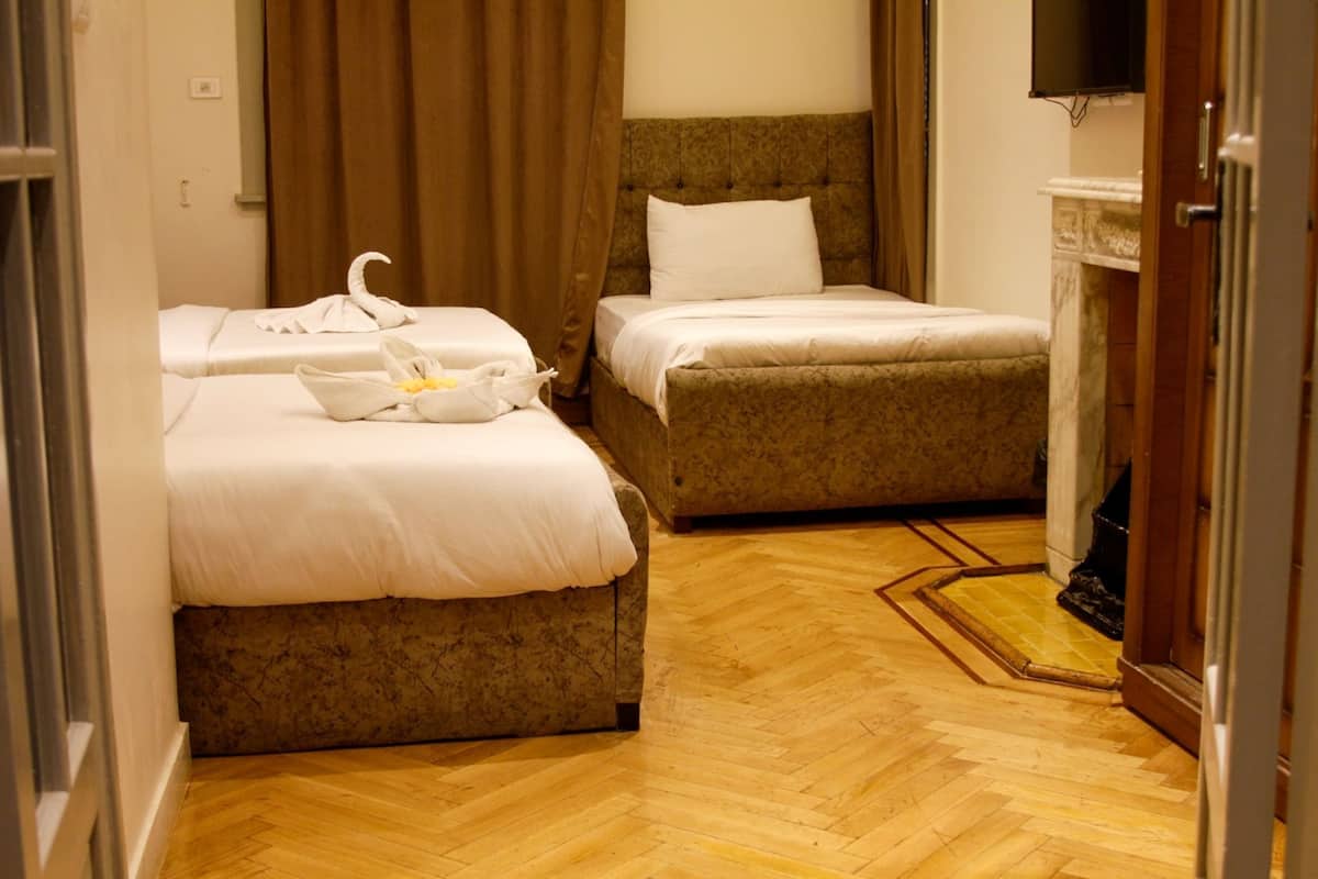 A hotel room with two beds, a television, and a fireplace.