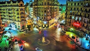A nighttime view of a city square with a roundabout, surrounded by historic buildings with classical architecture. - Yacoubian Hotels (Cairo)