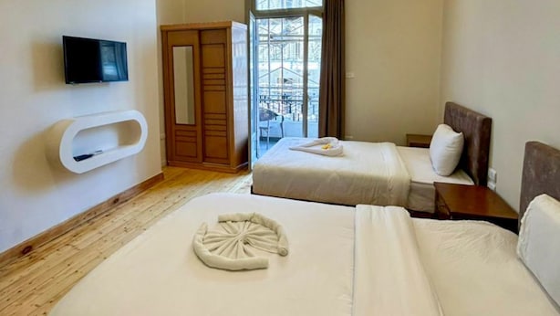 A hotel room with two beds, a TV, a wardrobe, and a window with a view. - Yacoubian Hotels (Cairo)