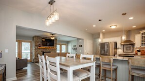 Una cocina moderna con chimenea de piedra, mesa de comedor de madera y taburetes de bar.