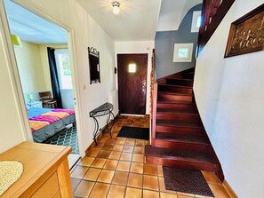 A hallway with a wooden staircase, a bed with a colorful blanket, a small table, and a chair. - Beautiful "Keristin" family home in Concarneau (Concarneau)