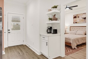 A bedroom with a bed, a nightstand, a coffee maker, and a shelf with decorative items. - Cozy Home by Medical Center and Downtown! Lydia A (Houston)
