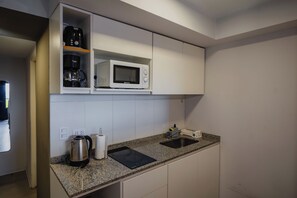 Una cocina moderna equipada con microondas, cafetera y hervidor.